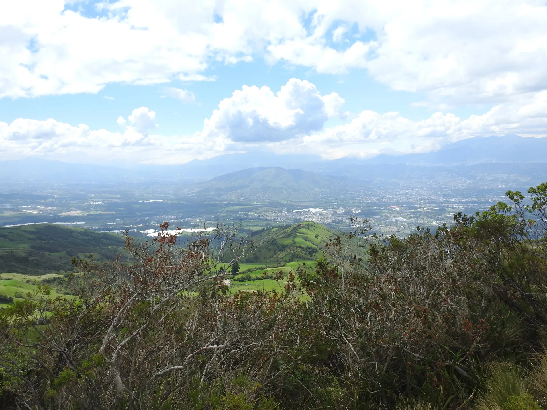 Vista del valle de Tumbaco y Pifo desde el cerro, con zonas verdes y urbanizaciones al fondo.